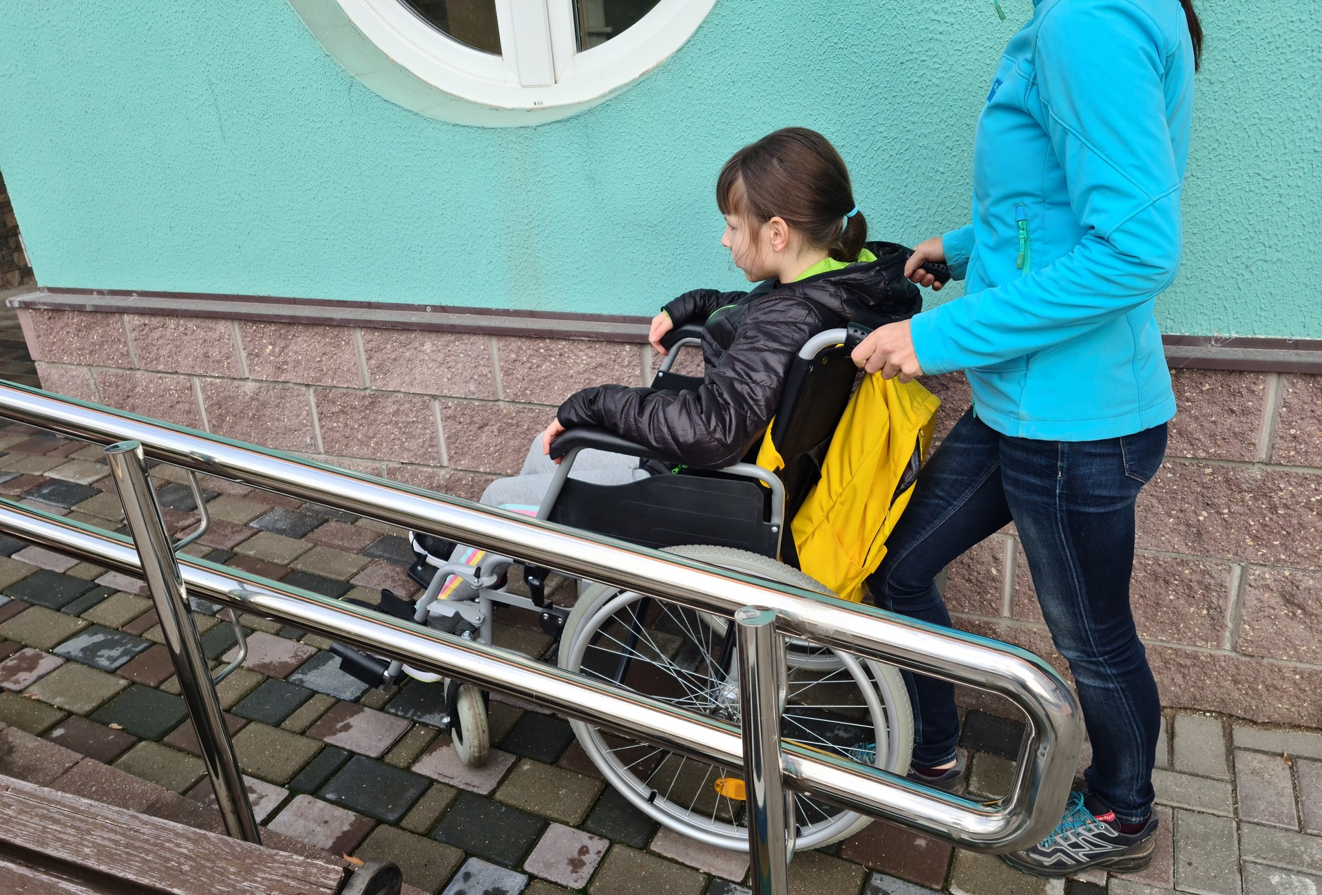 Woman Assisting Person in Wheelchair on a Ramp