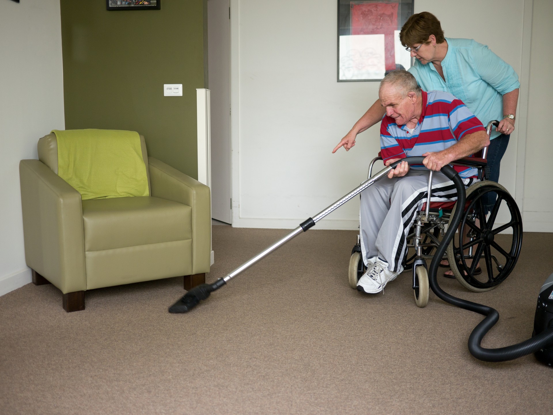 Sixty-six year old man vacuuming